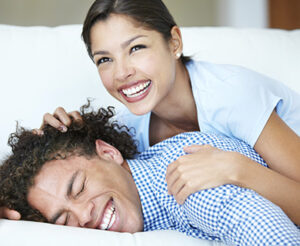 A woman and young man laughing and smiling together in a reclined position.